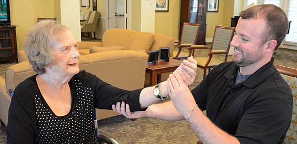 caregiver helping elderly woman stretch her arm